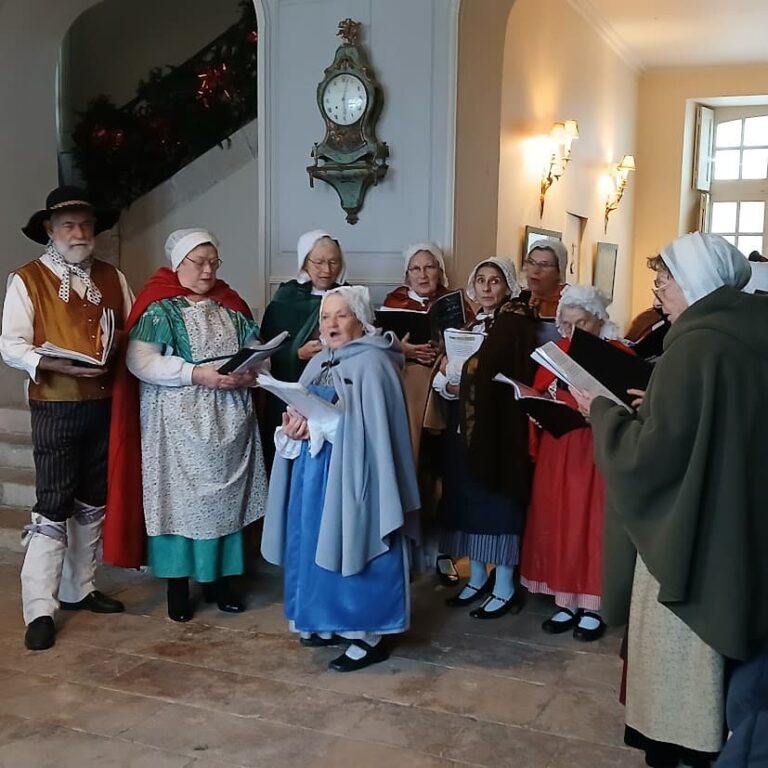 Figurants costumés chantant des chants de Noël dans l’escalier du château