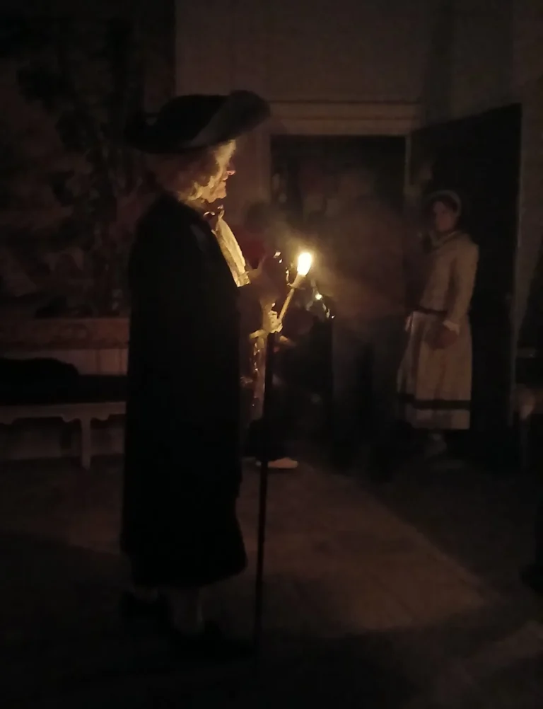 Deux figurants costumés dans un salon, éclairés à la bougie